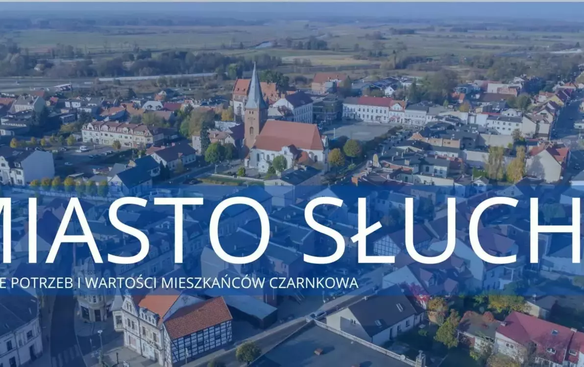 zdjęcie miasta z lotu ptaka z nałożonym niebieskim filtrem oraz białym napisem miasto słuch